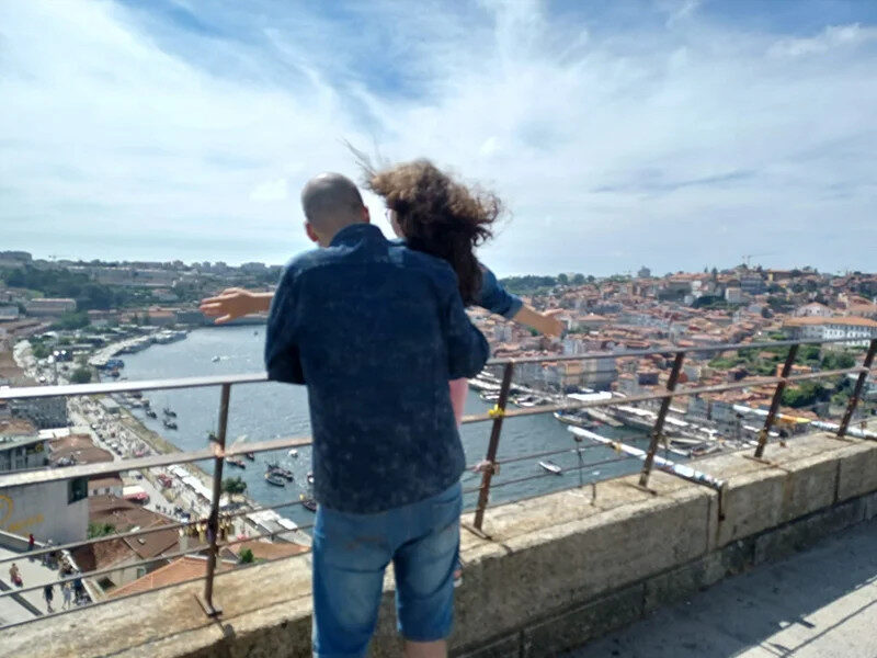 Copywriter Márcio Matos e e filha de costas, contemplando a paisagem do Porto, simbolizando inspiração e valores familiares.
