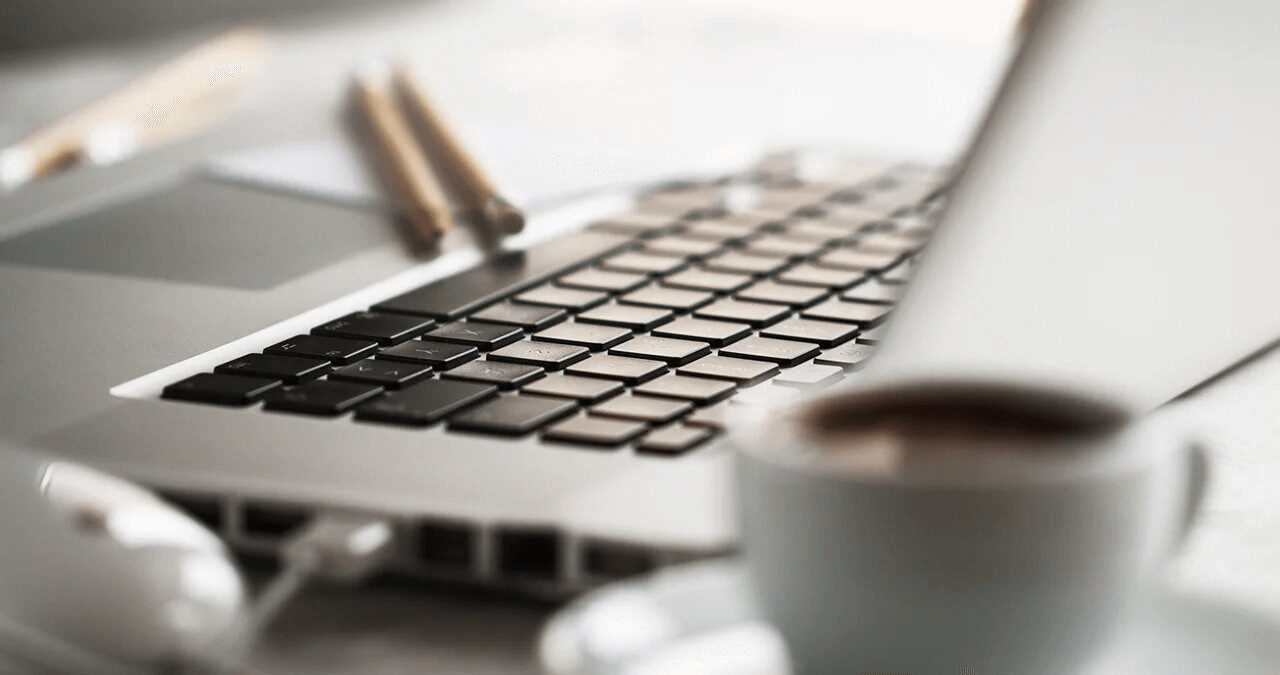 Portátil em destaque com fundo desfocado de café, simbolizando o ambiente de trabalho do copywriter.